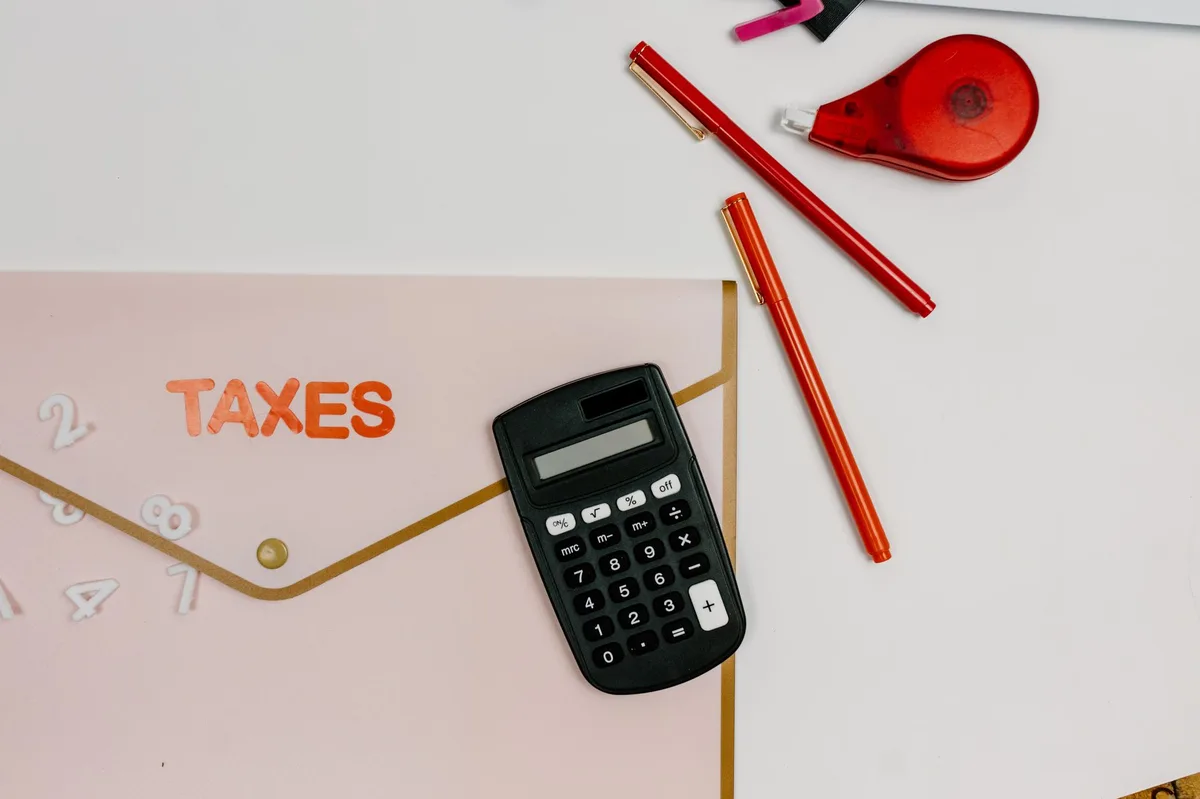 Dirigeant de TPE comparant ses documents comptables et sa calculatrice sur son bureau