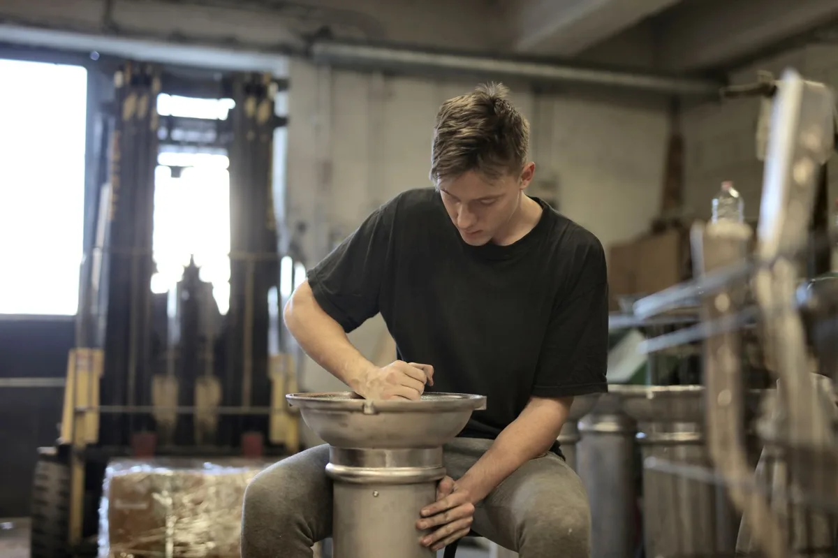 Jeune alternant formé par un tuteur devant un ordinateur dans un atelier
